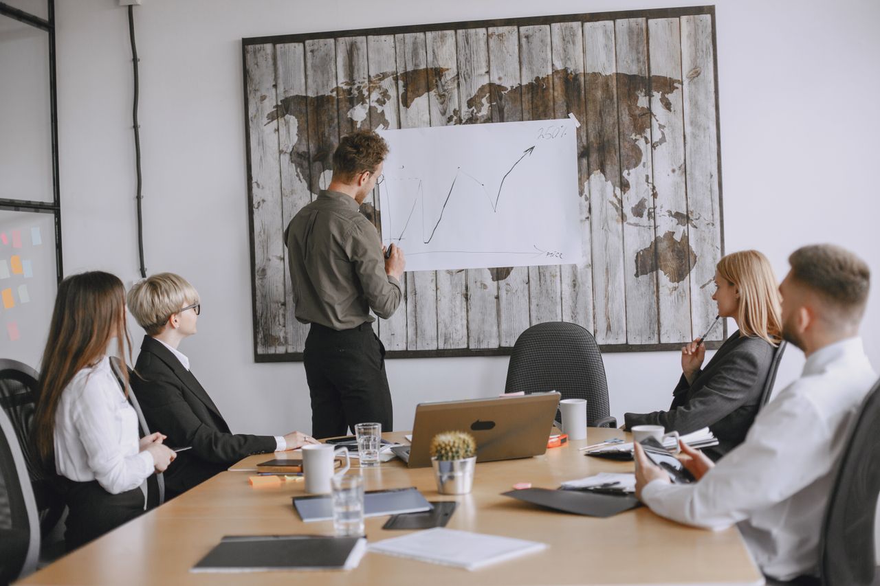 Services Group of business professionals discussing strategies with growth chart in conference room.