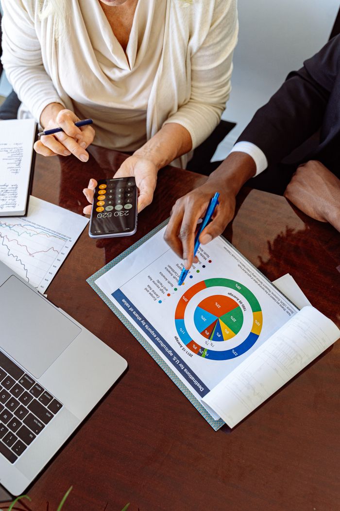 Services Two business professionals discussing financial documents and strategies at an office desk.