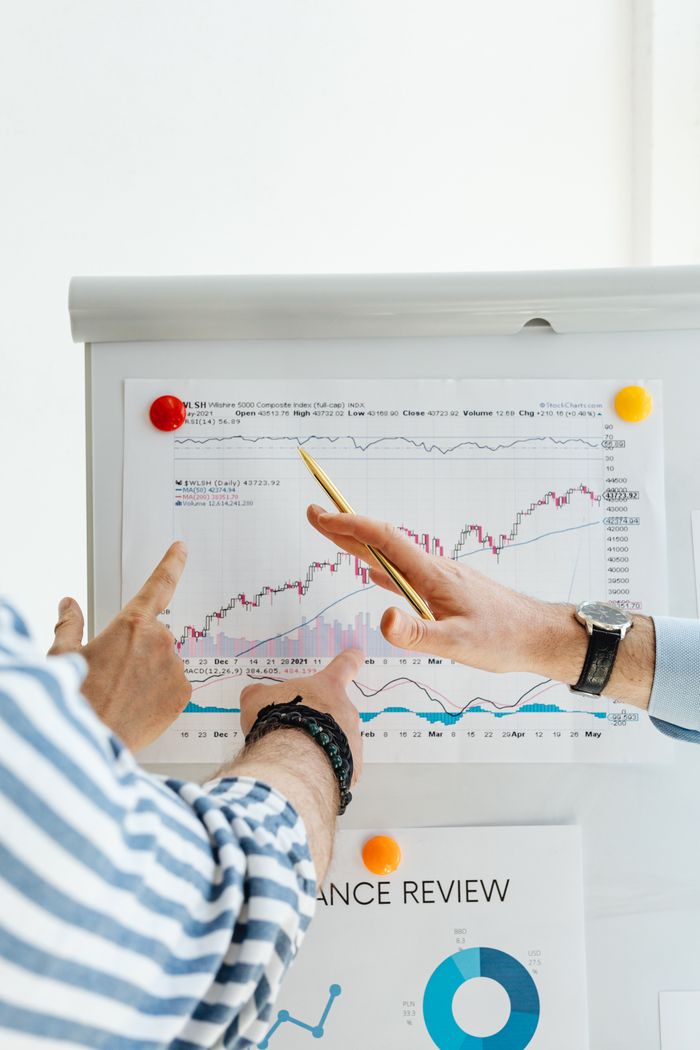 Services Two people analyzing financial charts on a whiteboard during a business meeting.