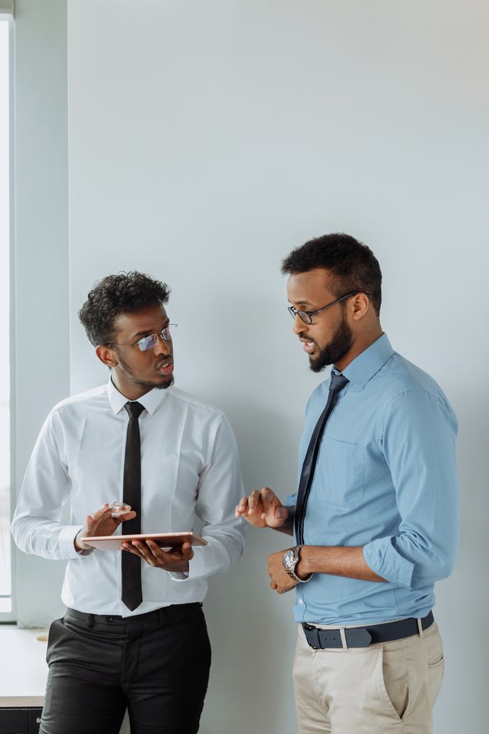 Services Two professionals discussing plans using a tablet in a modern office setting.
