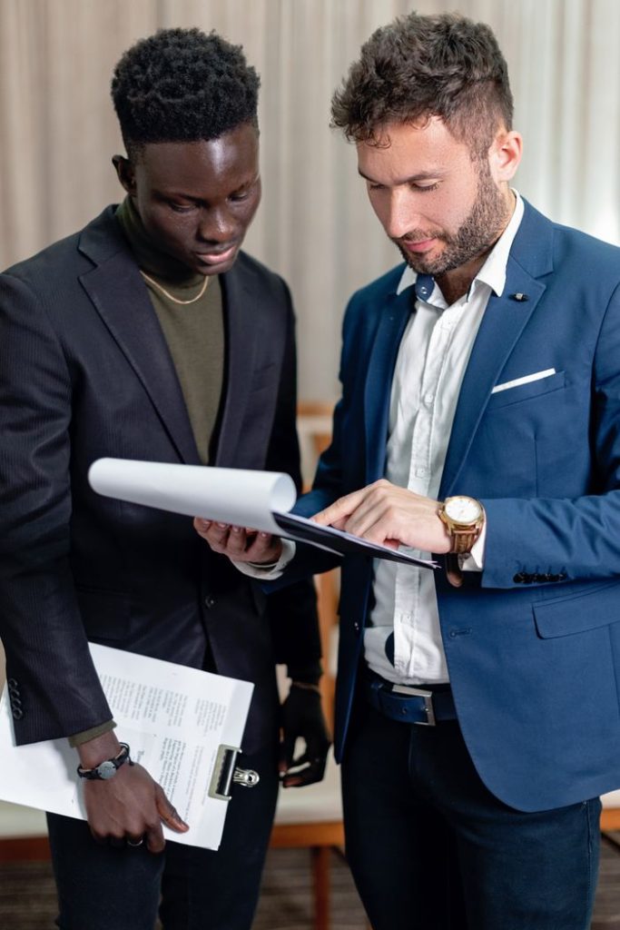 Mastering the First Impression: Your intriguing post title goes here Two business professionals in corporate attire reviewing documents indoors.