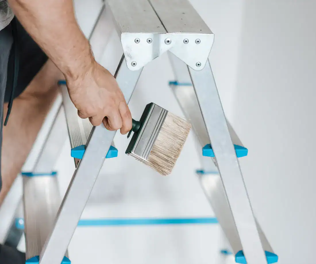 Painter and decorator holding a brush by a stepladder