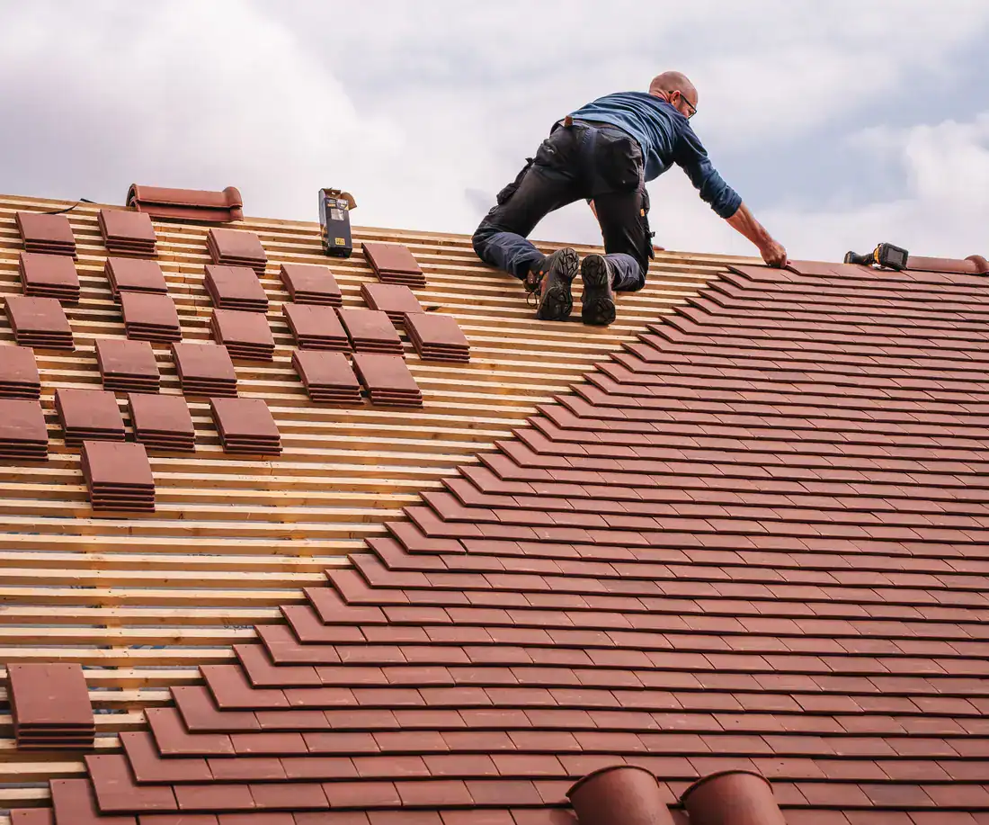 Roofer laying new roof tiles
