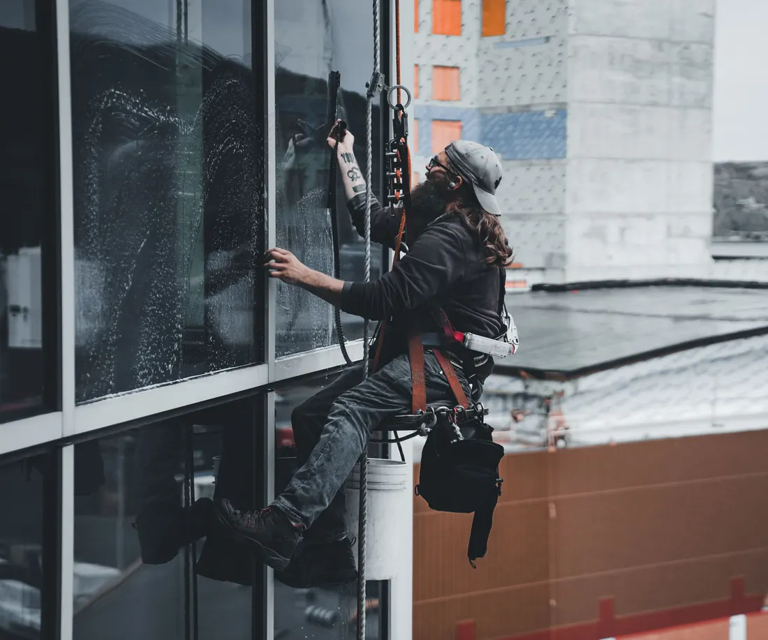 Window cleaner on ropes cleaning high windows