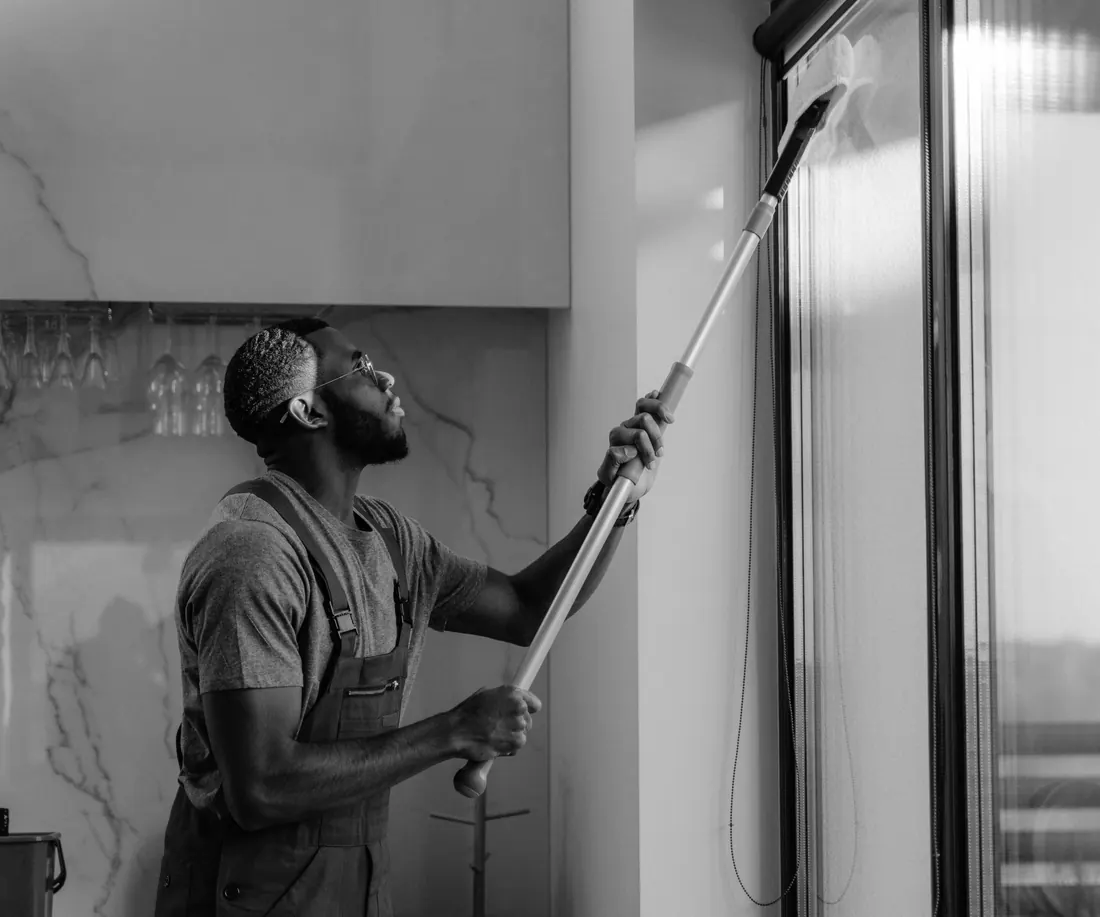 Window cleaner cleaning a tall window with a pole